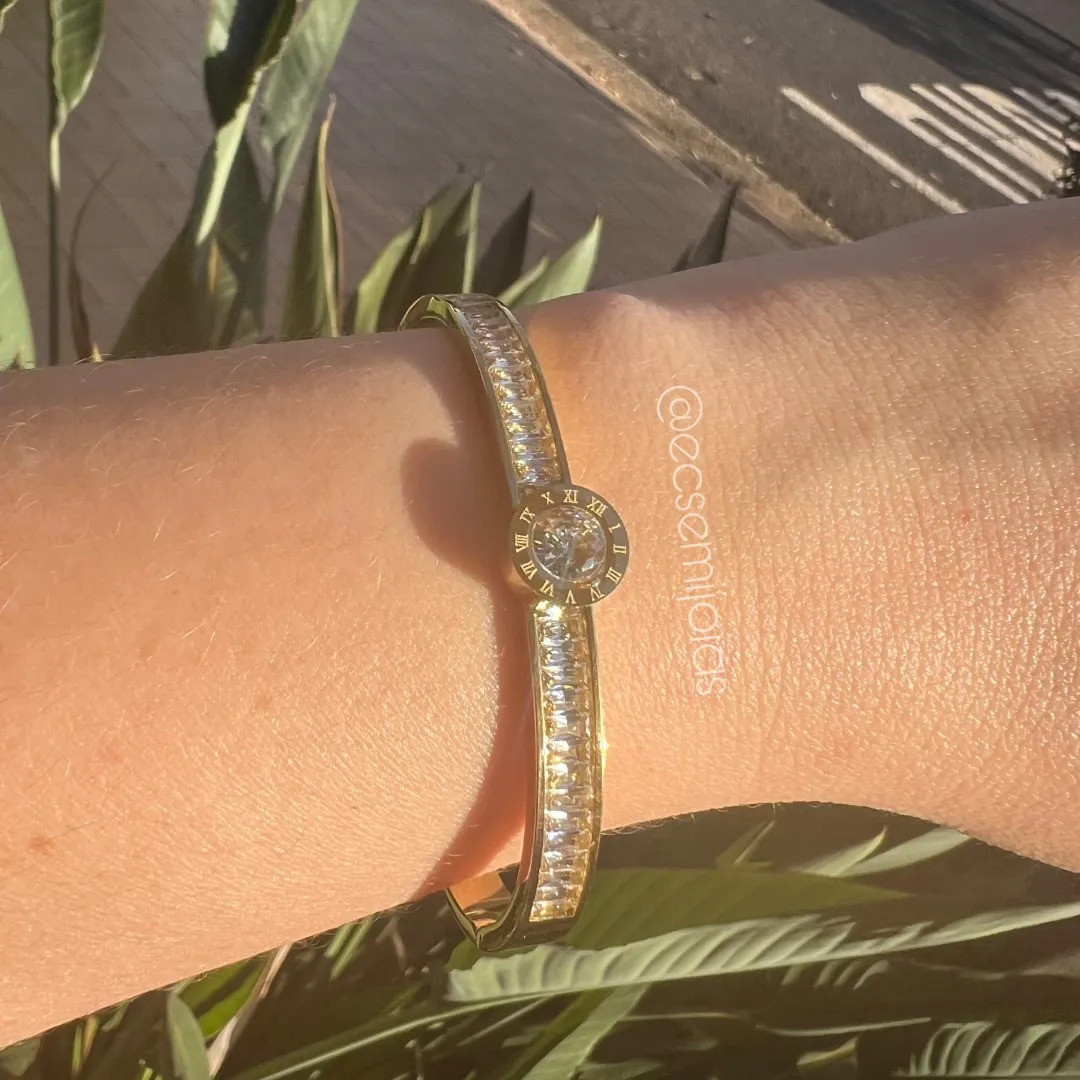 Bracelete com zircônia redonda no centro com borda com números gregos e aro cravejado com zircônias baguetes - aço dourado